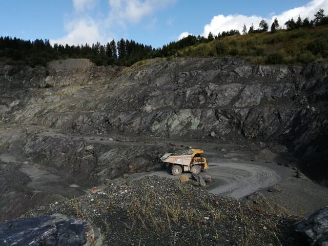 Radlader in der Sohle des Steinbruchs vor der Abbauwand